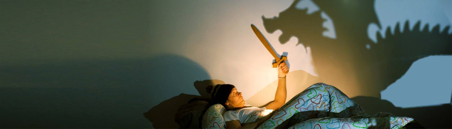 Mann liegt im Bett und kämpft mit einem Schattendrachen (Foto: kallejipp / photocase.de)