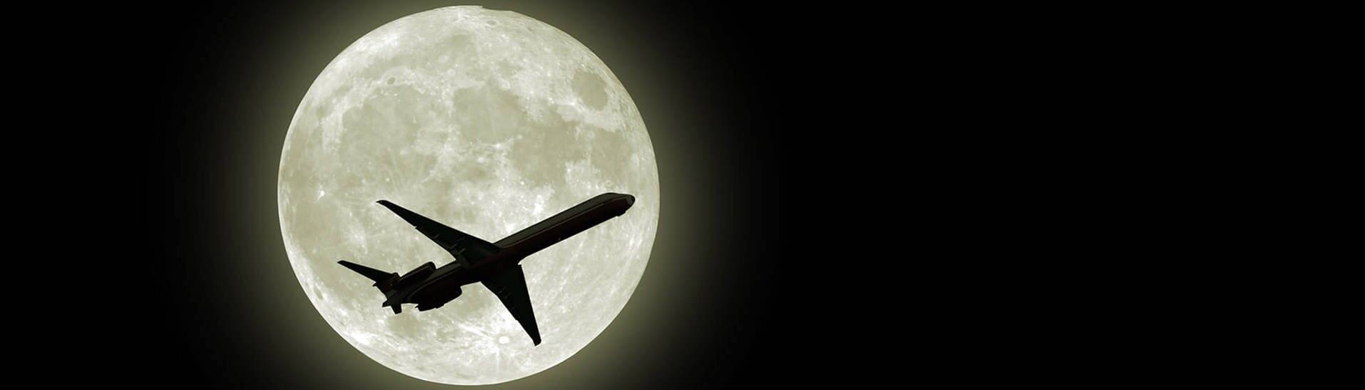 Flugzeug fliegt vor dem Mond (Foto: AdobeStock / photoncatcher36)