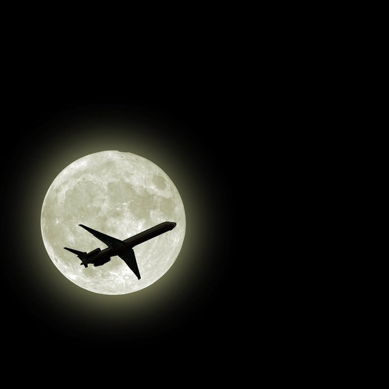Flugzeug fliegt vor dem Mond (Foto: AdobeStock / photoncatcher36)