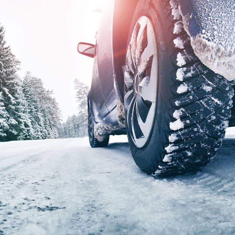 Auto mit Winterreifen auf schneebedeckter Straße (Foto: Adobe Stock / candy1812)