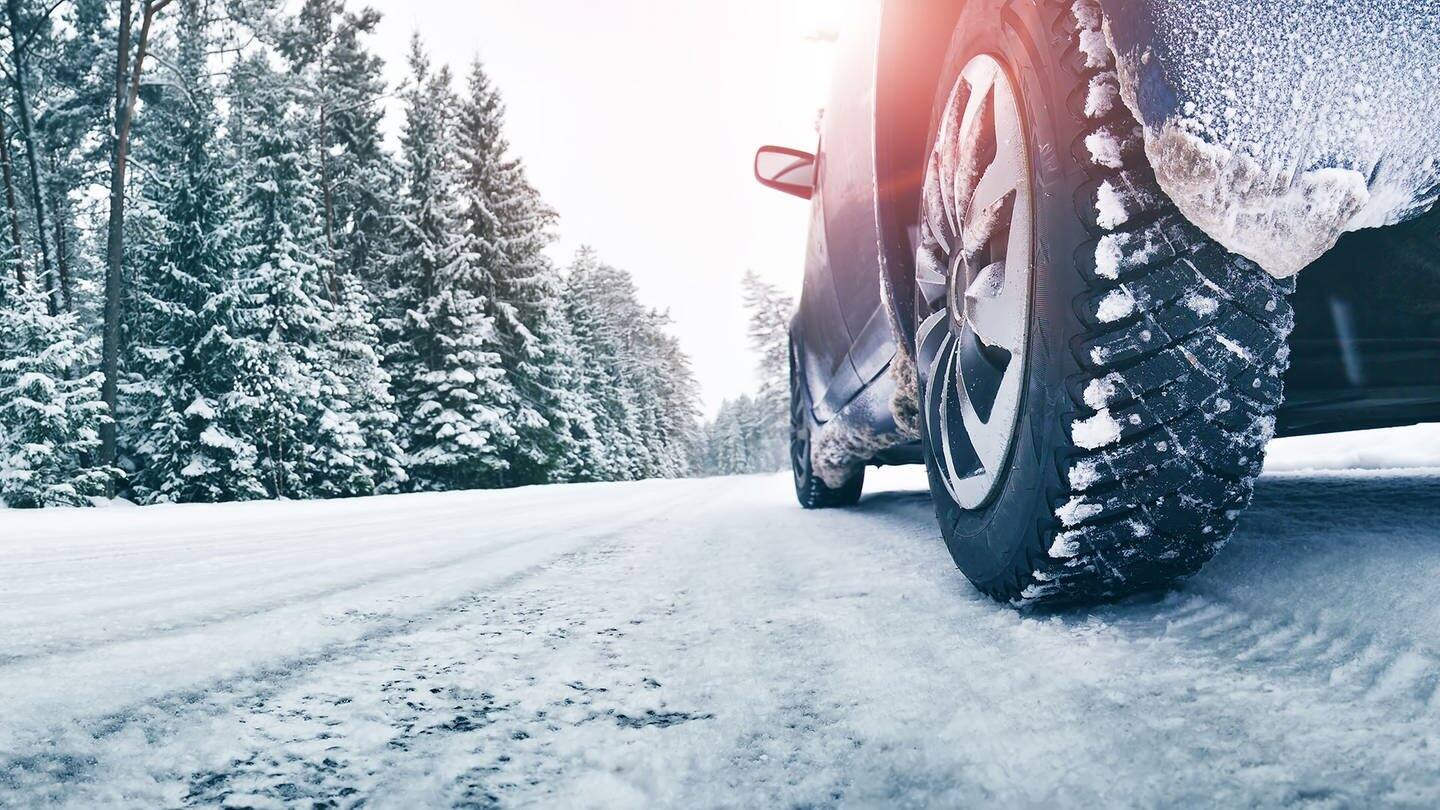 Auto mit Winterreifen auf schneebedeckter Straße (Foto: Adobe Stock / candy1812)