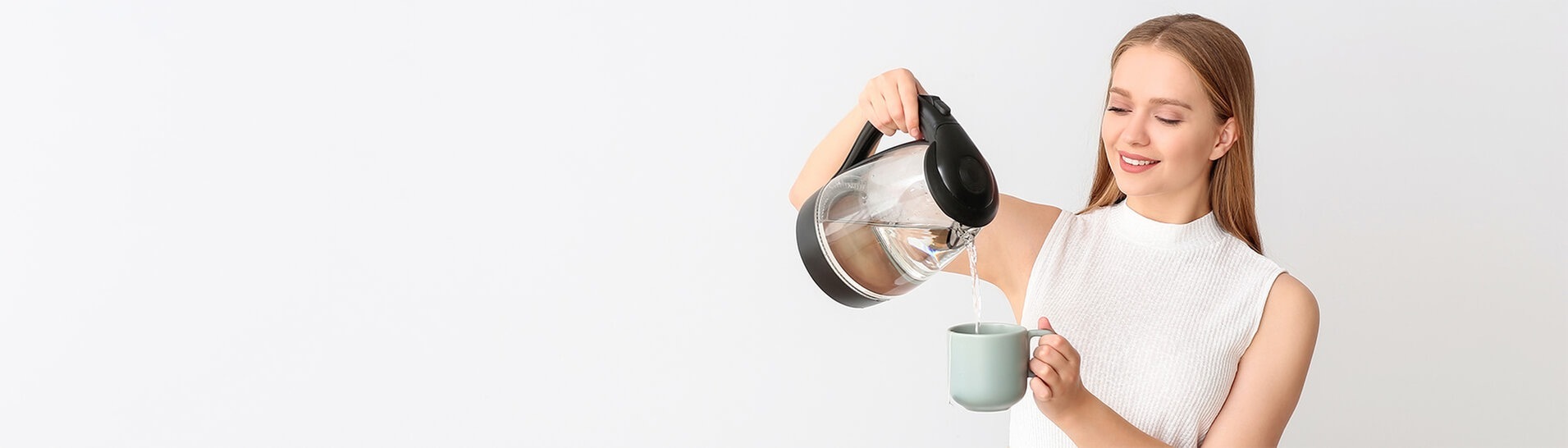 Frau schenkt sich aus dem Wasserkocher Wasser in eine Tasse ein (Foto: Adobe Stock / Pixel-Shot)