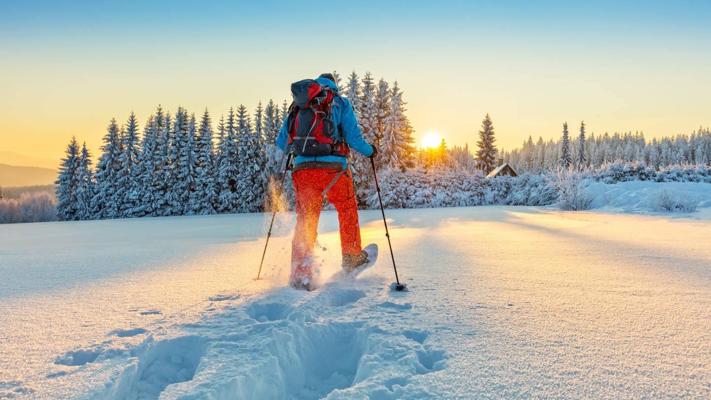Schneeschuhwanderer läuft der Sonne entegegen (Foto: Adobe Stock/Jag_cz)