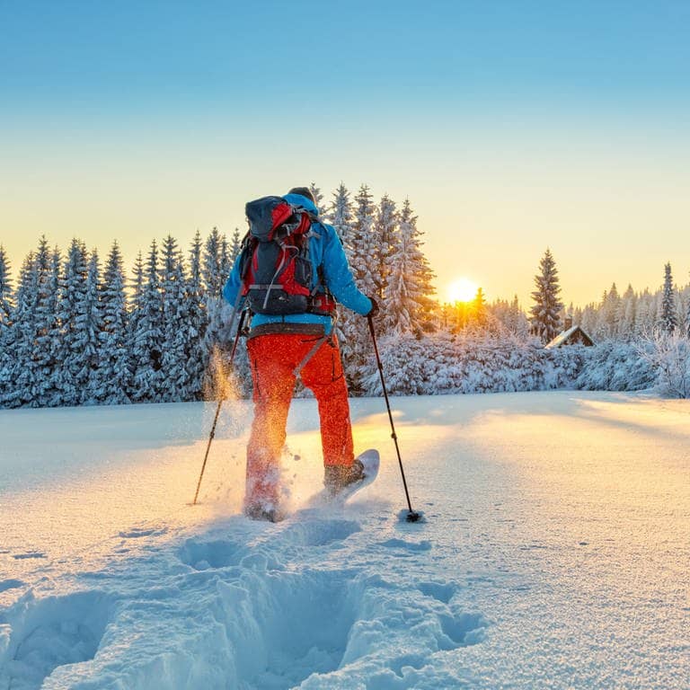 Schneeschuhwanderer läuft der Sonne entegegen (Foto: Adobe Stock/Jag_cz)