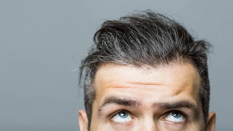 Mann schaut besorgt auf sein grau werdendes Haar  (Foto: Adobe Stock/Volodymyr)