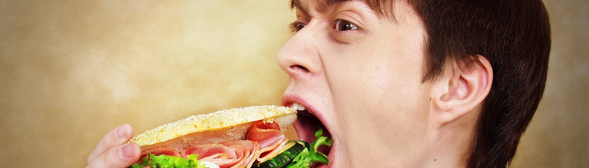 Mann der ein Sandwich isst (Foto: Adobe Stock / Natalia Uzkova)