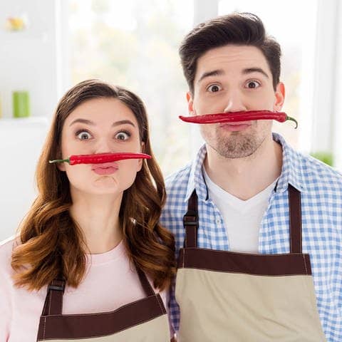 Paar hat Spaß in der Küche mit Peperoni-Schnurrbärten (Foto: Adobe Stock/deagreez)