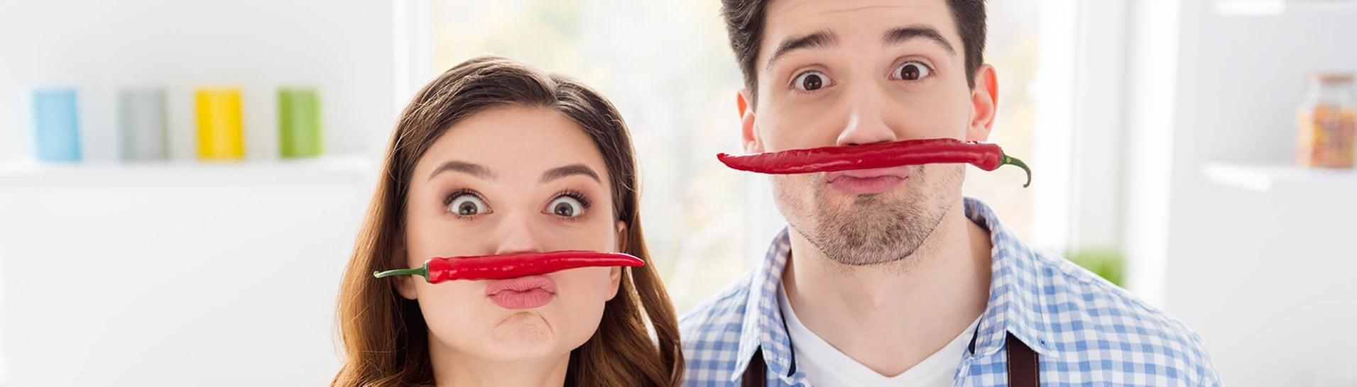 Paar hat Spaß in der Küche mit Peperoni-Schnurrbärten (Foto: Adobe Stock/deagreez)