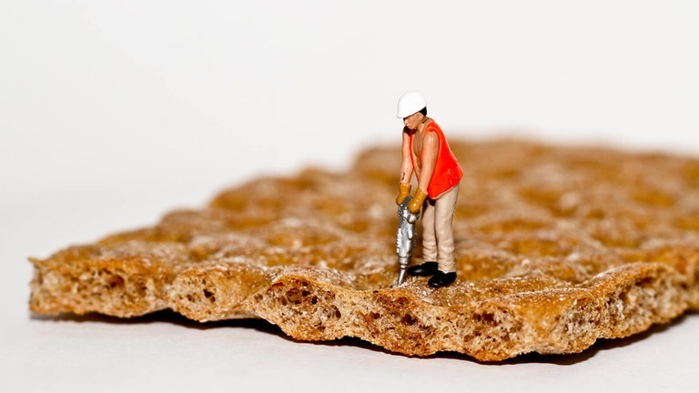Miniatur-Figur mit Presslufthammer auf Knäckebrot (Foto: Adobe Stock / Phil Daub)