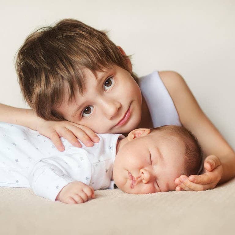 Älterer Bruder umarmt neugeborenes Baby (Foto: Adobe Stock / nfbiruza)