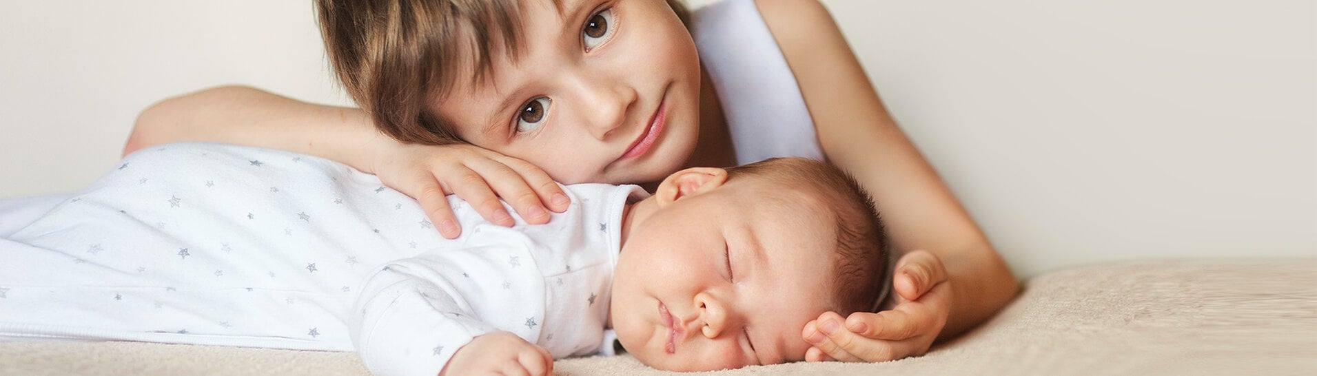 Älterer Bruder umarmt neugeborenes Baby (Foto: Adobe Stock / nfbiruza)
