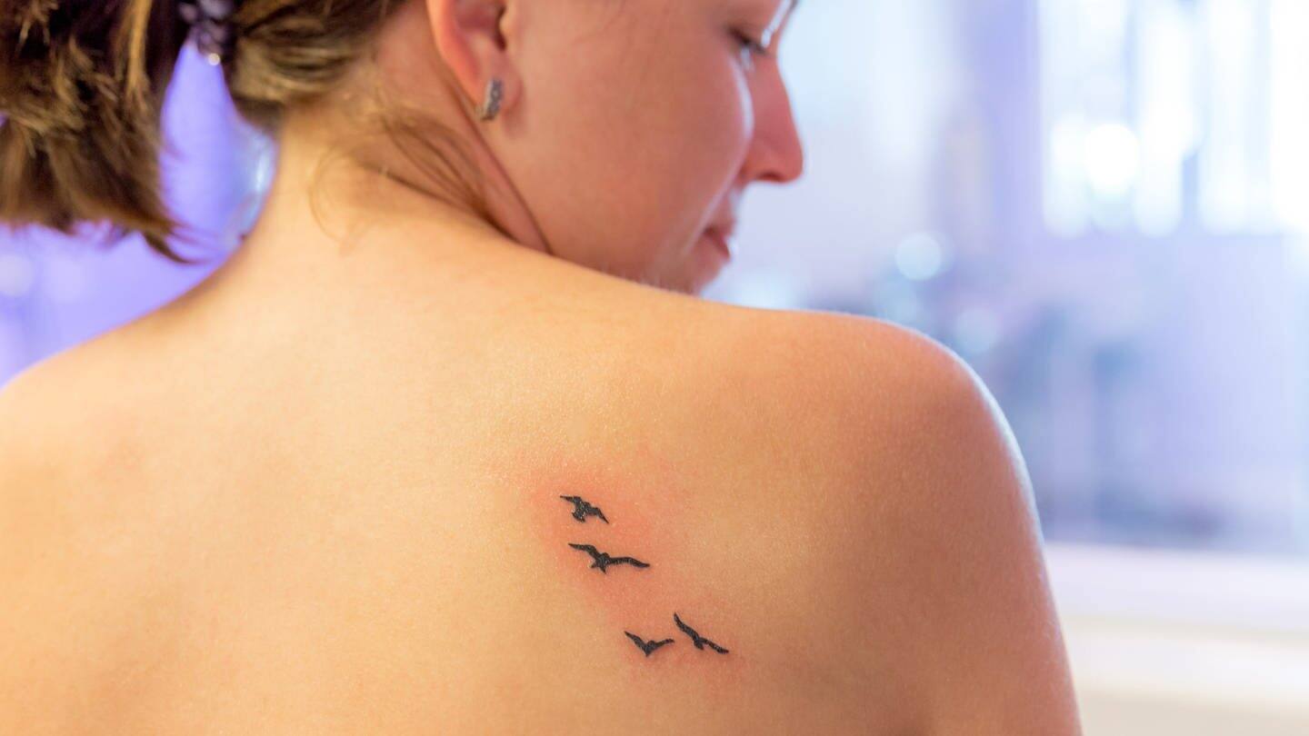 Frisches Tattoo mit fliegenden Vögeln auf dem Rücken einer jungen Frau (Foto: Adobe Stock/Mariakray)