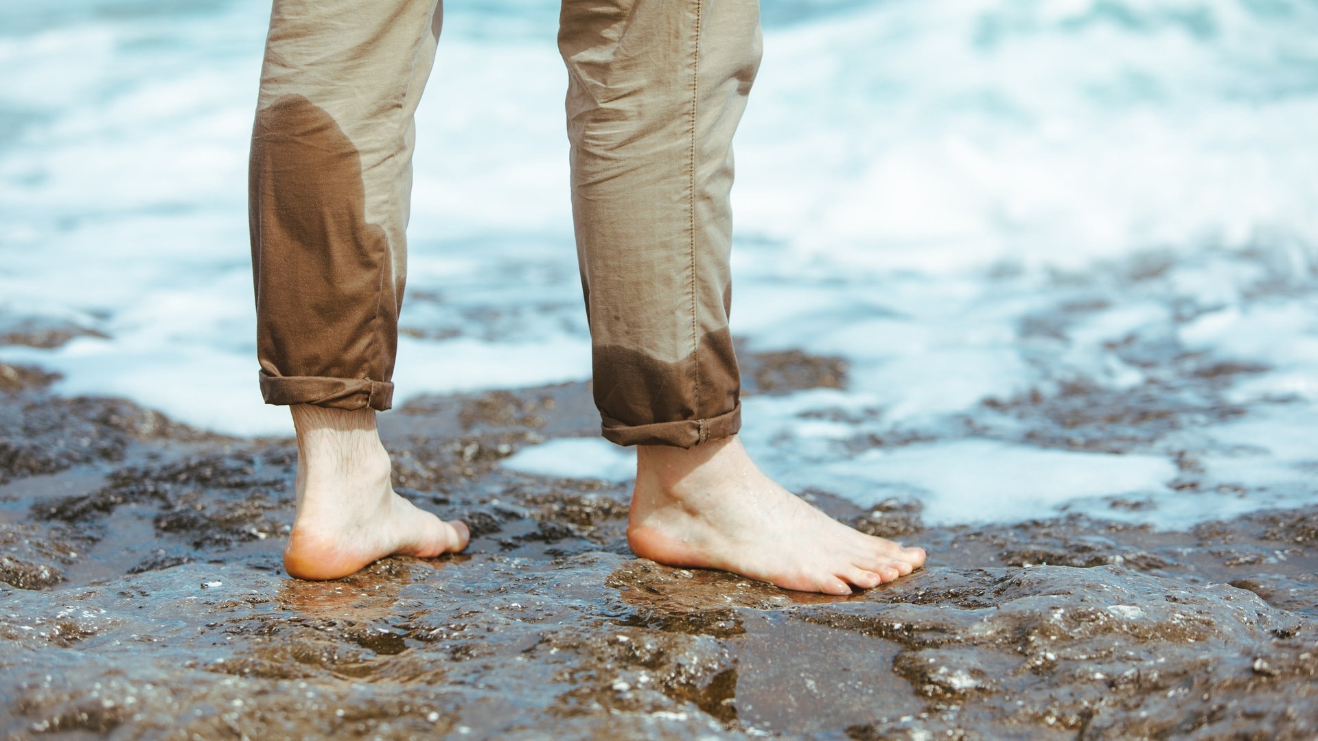 Mann mit halbnassen Hosenbeinen steht im Wasser (Foto: Adobe Stock, phpetrunina14)
