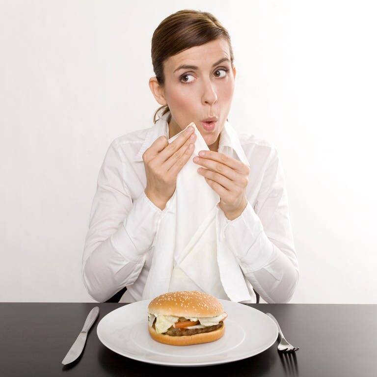 Junge Frau tupft sich beim Essen mit der Serviette den Mund ab (Foto: Adobe Stock, drubig-photo)