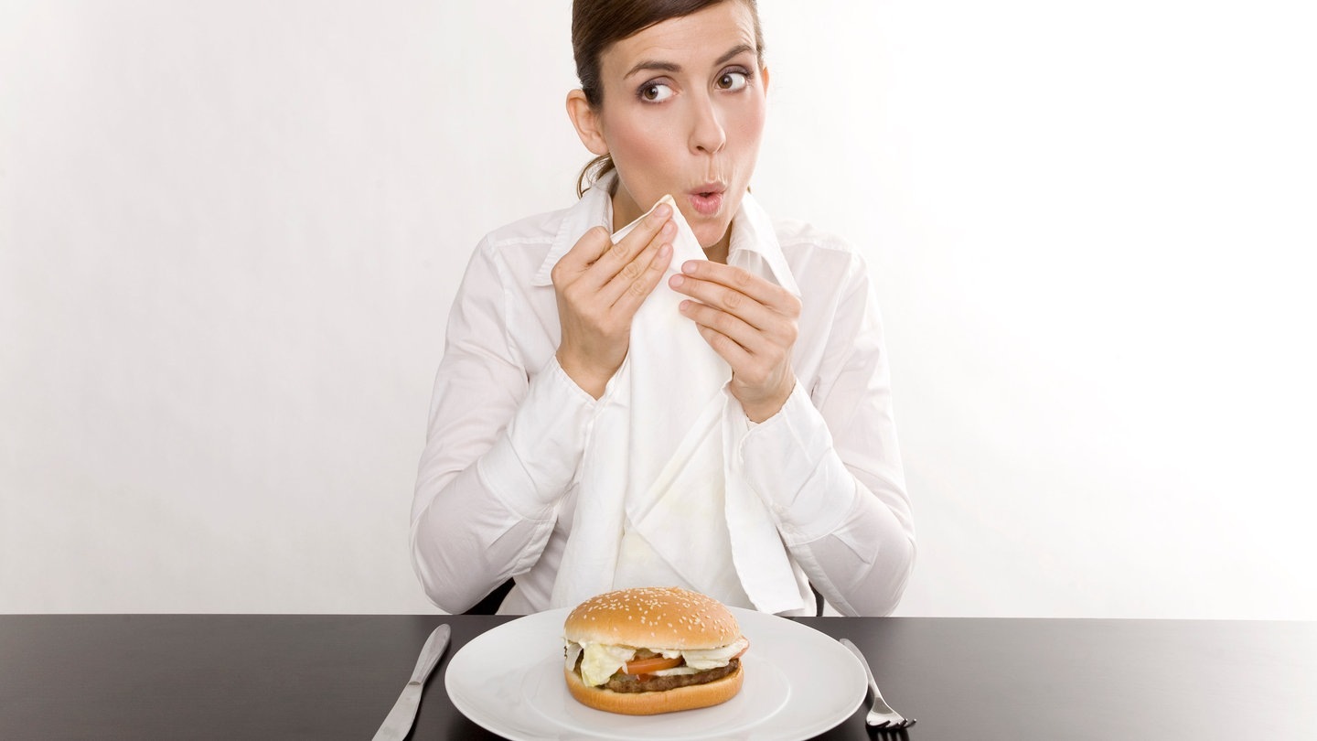 Junge Frau tupft sich beim Essen mit der Serviette den Mund ab (Foto: Adobe Stock, drubig-photo)