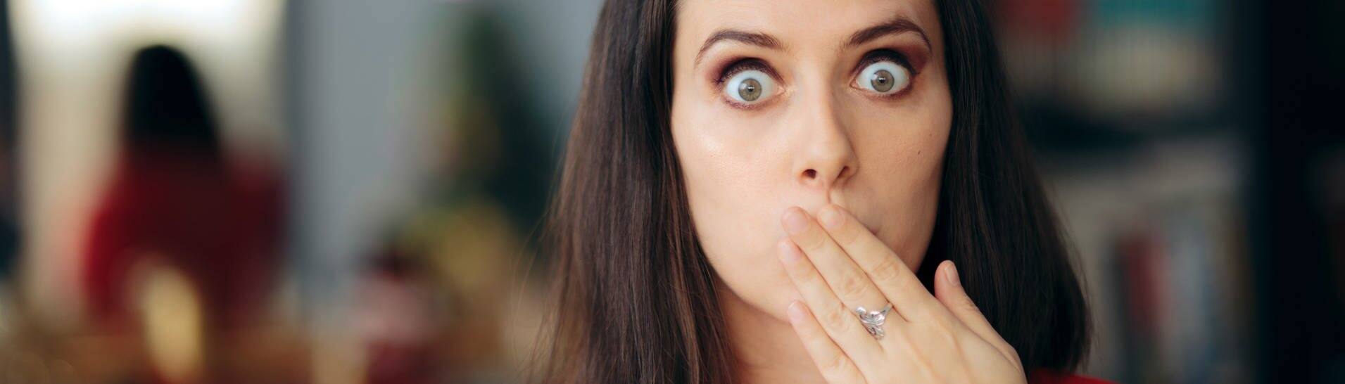 Frau mit erschrockenem Blick hält sich den Mund zu (Foto: Adobe Stock, nicoletaionescu)