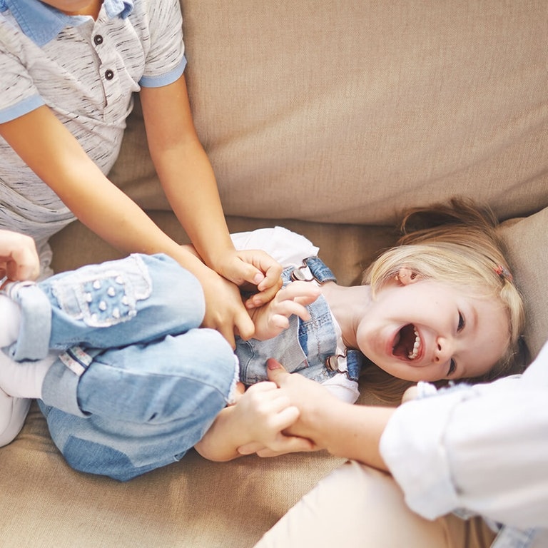 Mädchen wird von ihrer Familie gekitzelt und sie lacht (Foto: AdobeStock pressmaster)