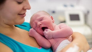 Mutter mit Neugeborenen im Kreißsaal