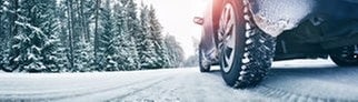 Auto mit Winterreifen auf schneebedeckter Straße