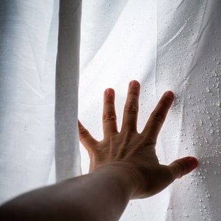 Hand am nassen Duschvorhang