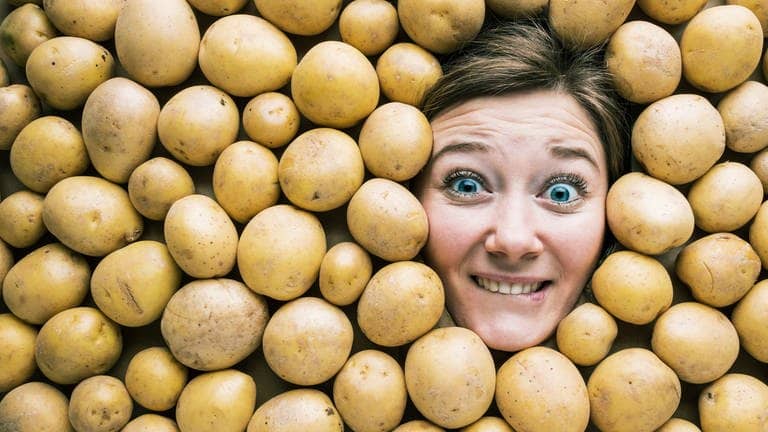 Gesicht einer Frau in einer Fläche aus Kartoffeln