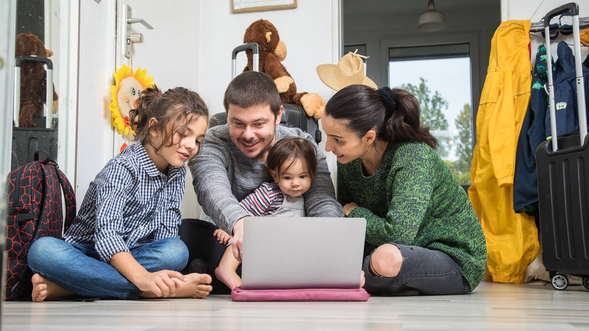 Eine Familie mit zwei kleinen Kindern sitzt vor dem Laptop und plant den nächsten Urlaub (Foto: picture-alliance / Reportdienste, picture alliance / dpa-tmn | Christin Klose)