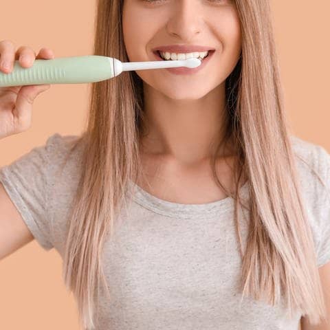 Frau putzt Zähne mit elektrischer Zahnbürste (Foto: Adobe Stock/Pixel Shot)
