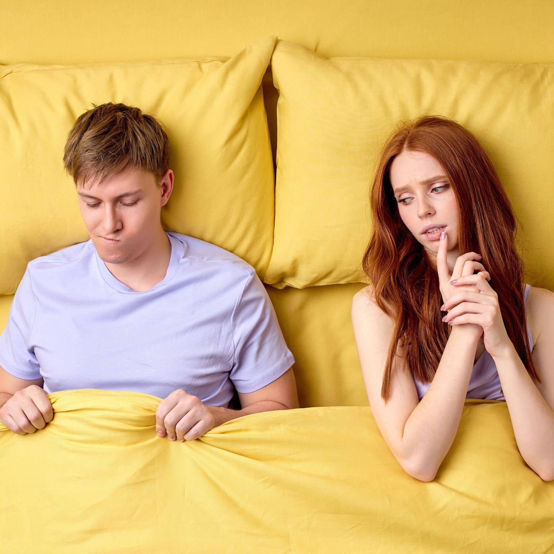 Junges Paar liegt im Bett. Sie schaut skeptisch zu ihm rüber, er ist verunsichert, weil er keine Lust hat auf Sex. (Foto: Afobe Stock/Roman)
