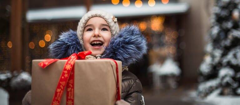 Ein Kind freut sich über ein Geschenk (Foto: dpa Bildfunk, Picture Alliance)