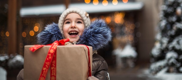 Ein Kind freut sich über ein Geschenk (Foto: dpa Bildfunk, Picture Alliance)