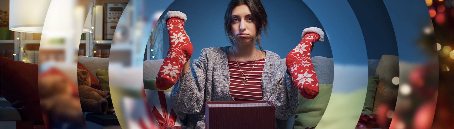 Eine Frau freut sich nicht über ein paar dicke Socken, dis sie gerade aus einem Geschenk ausgepackt hat. (Foto: Adobe Stock/StockPhotoPro)