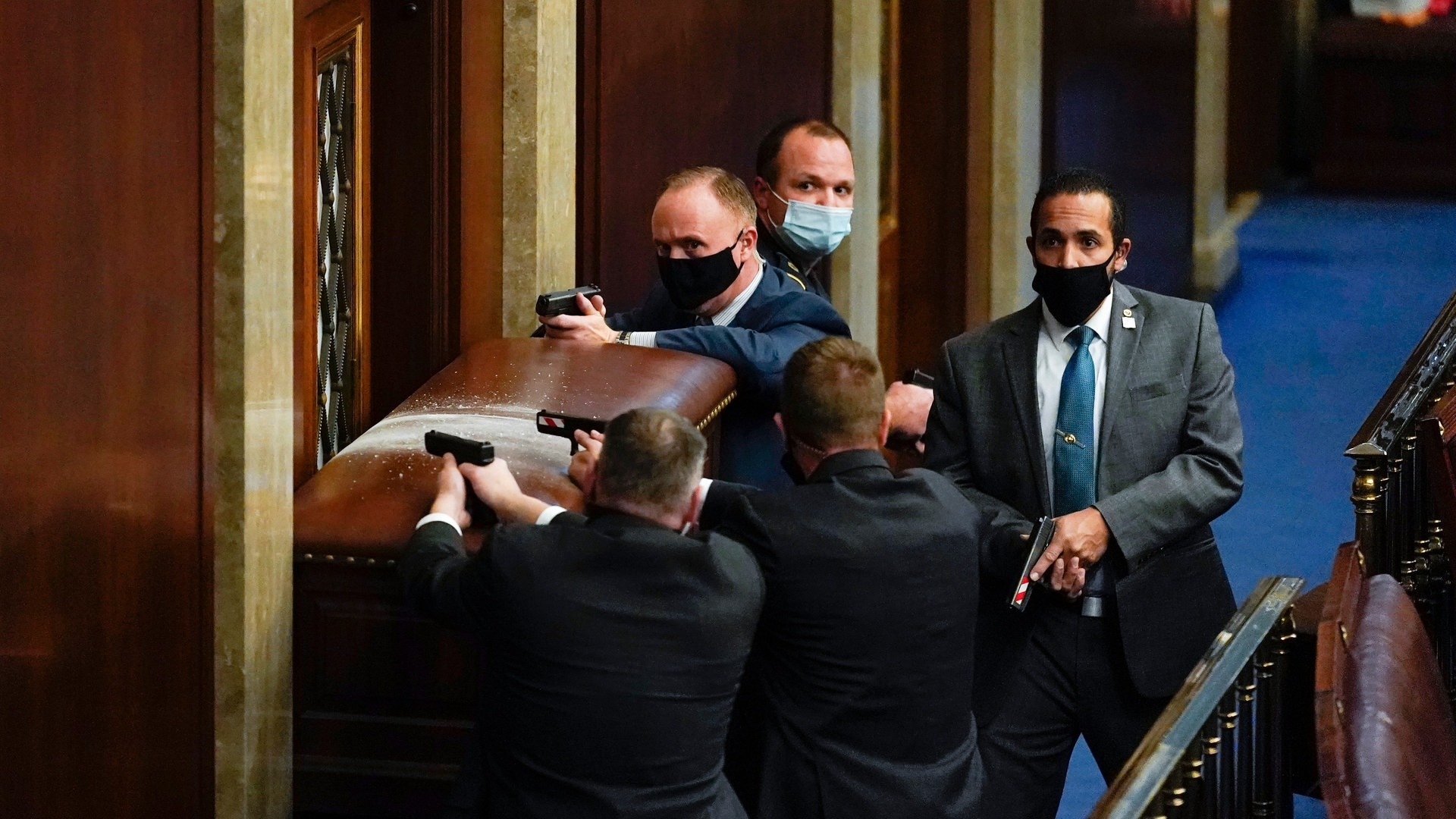 Foto: dpa Bildfunk, picture alliance/dpa/AP | Andrew Harnik U.S. Kapitol Polizisten stehen mit gezogenen Waffen in der Nähe einer verbarrikadierten Tür. (Foto: dpa Bildfunk, picture alliance/dpa/AP | Andrew Harnik)