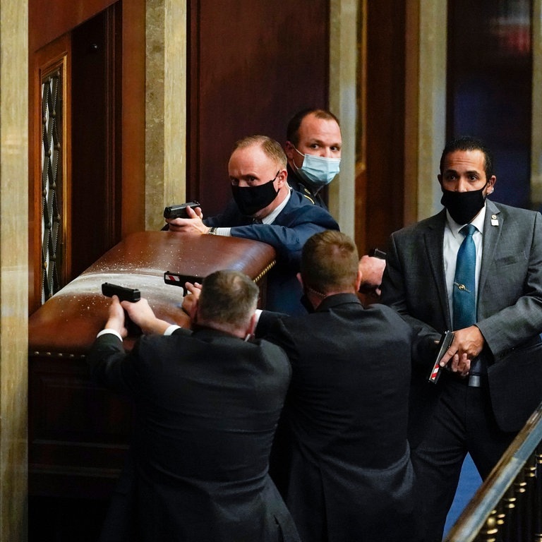 U.S. Kapitol Polizisten stehen mit gezogenen Waffen in der Nähe einer verbarrikadierten Tür. (Foto: dpa Bildfunk, picture alliance/dpa/AP | Andrew Harnik)
