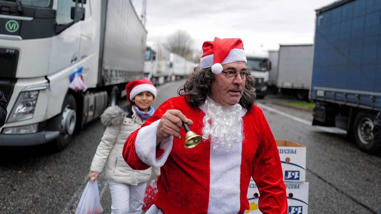 Juan Pedro Garcia Rosales in Weihnachtsmannkostüm klingelt mit einem Glöckchen auf dem Parkplatz zwischen Lkws. (Foto: SWR, Christof Gerlitz)