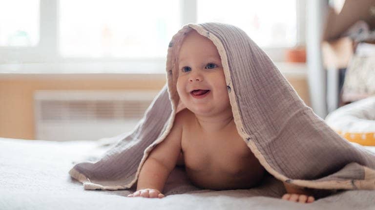 Ein Baby versteckt sich unter einer Decke (Foto: dpa Bildfunk, picture alliance/dpa | Annette Riedl)