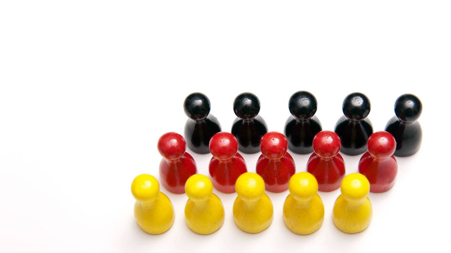 Schwarze, rote und gelbe Spielfiguren sind zu einer Deutschlandflagge angeordnet. (Foto: IMAGO, imago stock&people)