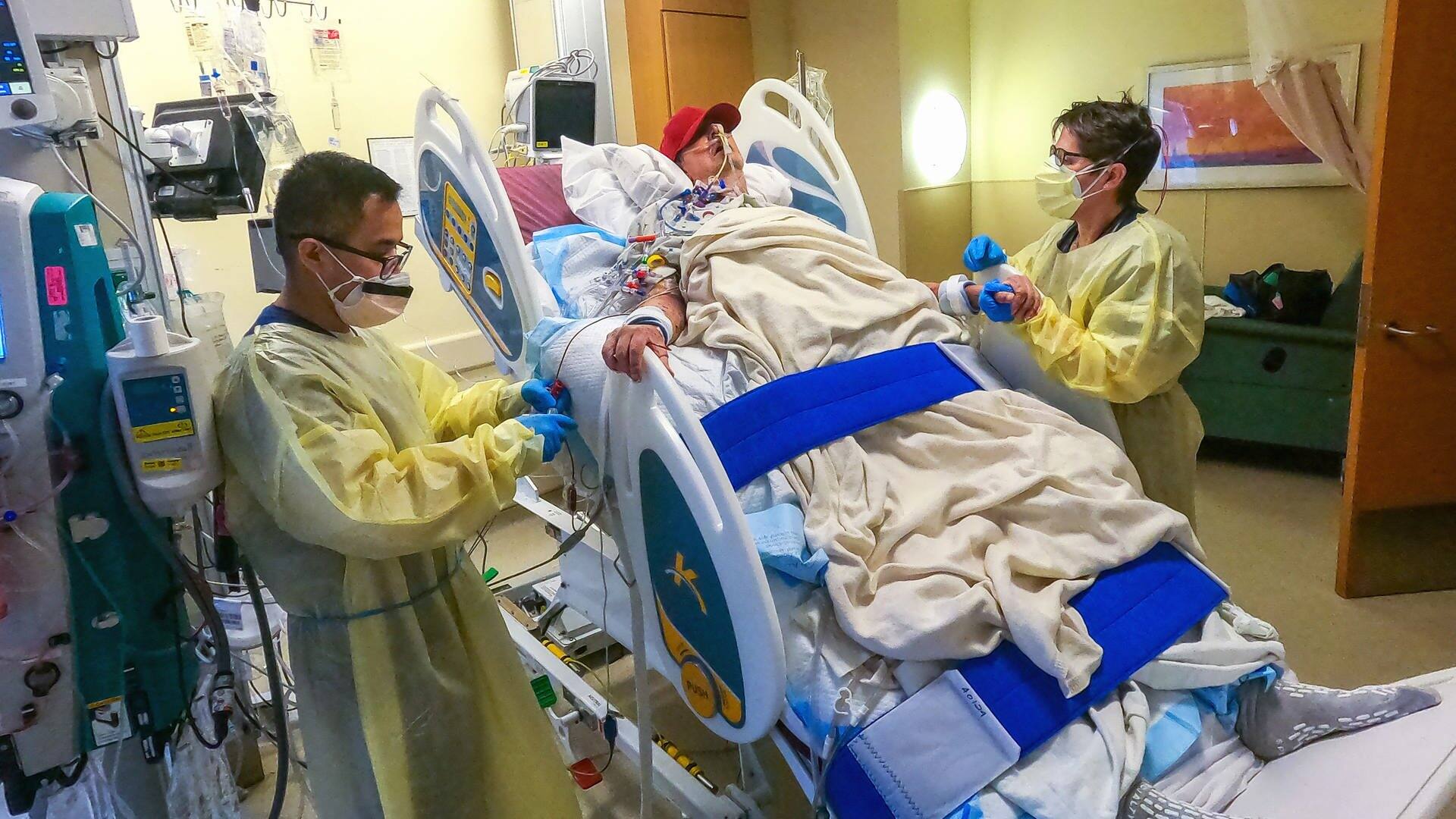 David Bennett in seinem aufgerichteten Klinikbett, rechts und links von ihm jeweils ein Physiotherapeut. (Foto: dpa Bildfunk, picture alliance/dpa/UMSOM Public Affairs | Tom Jemski)