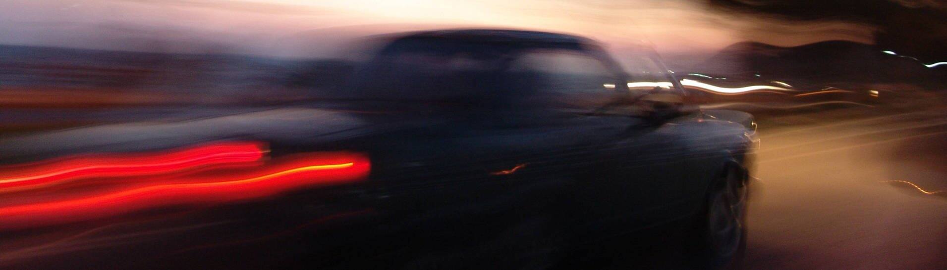 Auto fährt mit eingeschaltetem Licht durch die Dämmerung (Foto: IMAGO, imago/Jochen Tack)