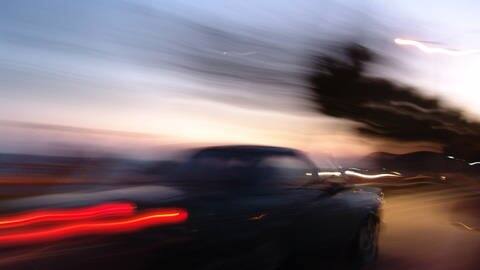 Auto fährt mit eingeschaltetem Licht durch die Dämmerung (Foto: IMAGO, imago/Jochen Tack)