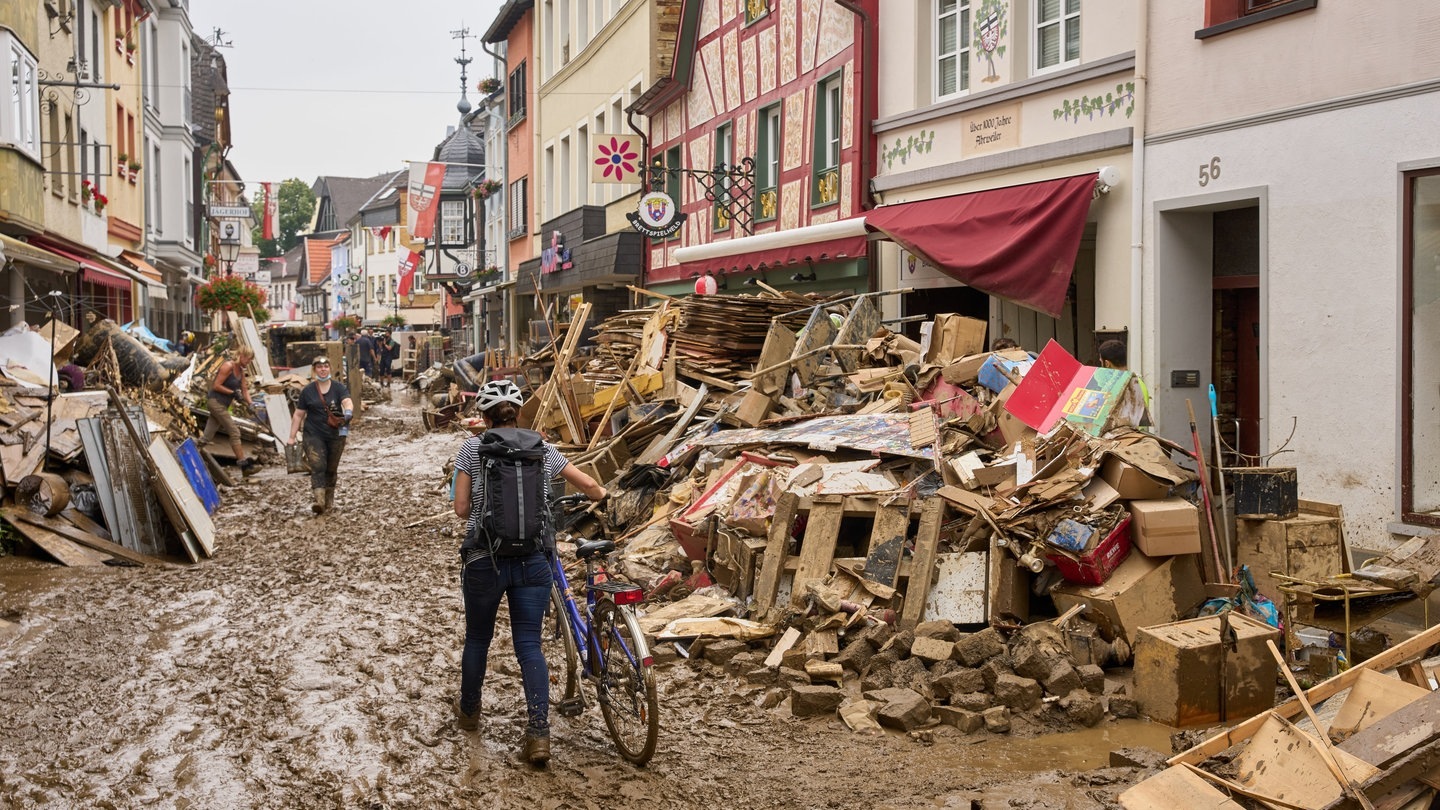 Ahrweiler: Eine Frau schiebt ihr Fahrrad durch den Schlamm.
