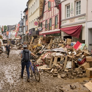 Ahrweiler: Eine Frau schiebt ihr Fahrrad durch den Schlamm.