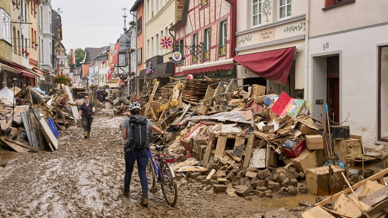 Ahrweiler: Eine Frau schiebt ihr Fahrrad durch den Schlamm. (Foto: dpa Bildfunk, picture alliance/dpa | Thomas Frey)