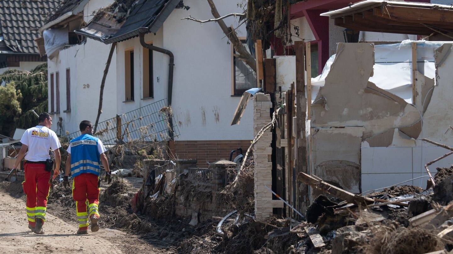 Retter gehen durch eine zerstörte Straße in Altenahr (Foto: dpa Bildfunk, picture alliance/dpa | Boris Roessler)