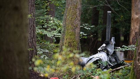 Trümmerteile des Hubschraubers vom Typ Robinson R44 und Feuerlöscher liegen in einem Wald bei Buchen nahe der Grenze zu Hessen und Bayern. (Foto: dpa Bildfunk, picture alliance/dpa | Sebastian Gollnow)
