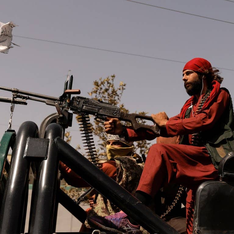 Taliban-Kämpfer sitzen hinter einem Maschinen-Gewehr auf einem Pickup in Kabul.