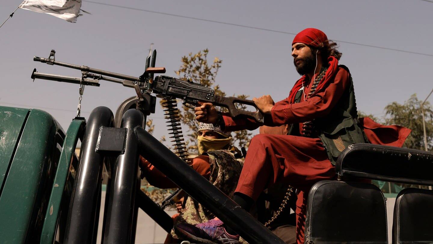 Taliban-Kämpfer sitzen hinter einem Maschinen-Gewehr auf einem Pickup in Kabul.