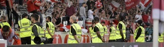 Ordner stehen im Stuttgarter Stadion vor der Tribüne mit VfB-Fans