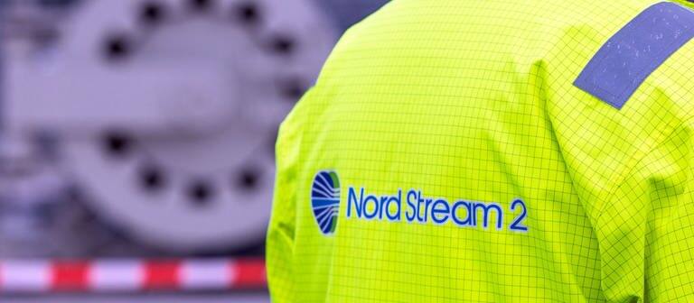 Ein Mitarbeiter mit einer Sicherheitsjacke von Nord Stream 2 steht vor der Molchstation in der Gasanlandestation von Nord Stream 2.  (Foto: dpa Bildfunk, picture alliance/dpa/dpa-Zentralbild | Jens Büttner)