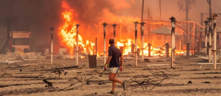 Ein Mann läuft und betrachtet den durch Feuer zerstörten „Le Capannine"-Strand in Catania auf Sizilien (Foto: )