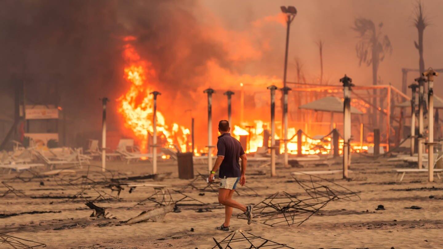 Ein Mann läuft und betrachtet den durch Feuer zerstörten „Le Capannine